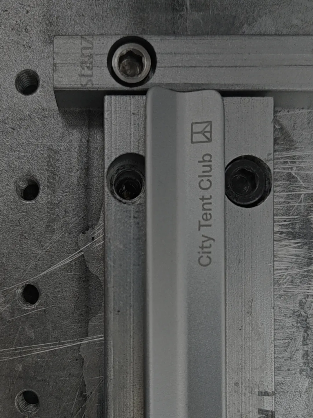 A silver tent stake held by clamps in a factory setting